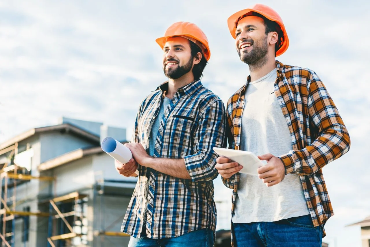 architects with blueprint and tablet looking away at construction site